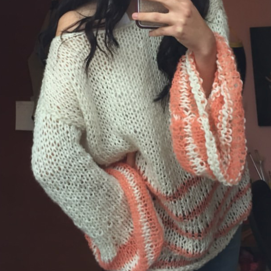 Person wearing a patterned sweater taking a mirror selfie with a phone.